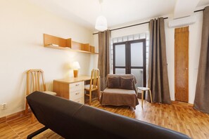 A room with a bed, desk, chair, and a small table.
