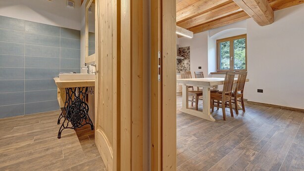 Une pièce avec un plafond en bois, un mur recouvert de carreaux, un coin repas avec des chaises et une table, et une fenêtre donnant sur un paysage agréable.