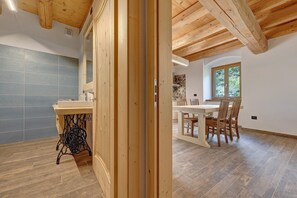 Ein Zimmer mit Holzboden, einer gefliesten Wand, einer Essecke mit Stühlen und Tisch sowie einem Fenster mit Blick.