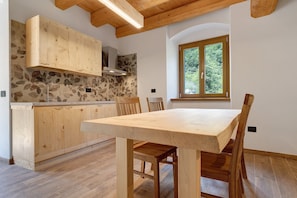 Une cuisine avec des meubles en bois, une grande fenêtre et une table à manger avec des chaises.