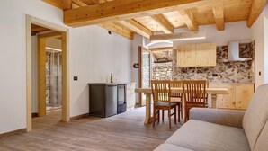 Une cuisine moderne avec des meubles en bois, un coin repas avec une table et des chaises en bois, et un salon avec un canapé.
