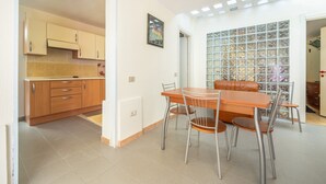 Un comedor con mesa y sillas de madera, una cocina con armarios de madera y un muro de vidrio con diseño de cuadrícula.