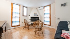 Una habitación con chimenea, dos sillones de mimbre, un sofá y una mesa de comedor.