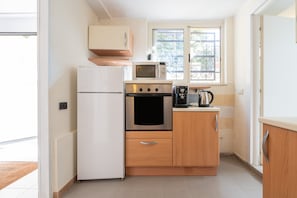 A compact kitchen with a refrigerator, oven, microwave, and coffee maker.