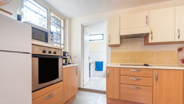 Una cocina con horno empotrado, microondas y una ventana sobre el lavamanos.