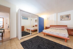 A bedroom with a bed, a wardrobe, a mirror, a dresser, and a chair.