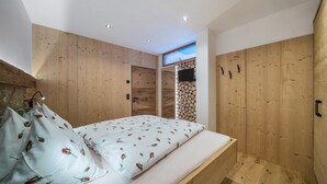 Een slaapkamer met een houten bed, een wandtelevisie en een houten kledingkast.
