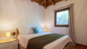 A bedroom with a bed, bedside lamps, a window with curtains, and a wooden ceiling. - Vacation Home "Villa Robi" near Beach with Private Terrace & Shared Garden (stintino)