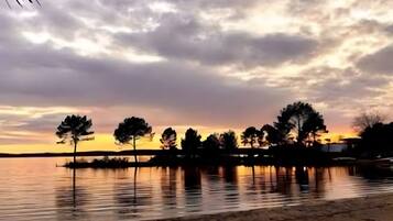 A sunset over a calm body of water with trees silhouetted against the sky.