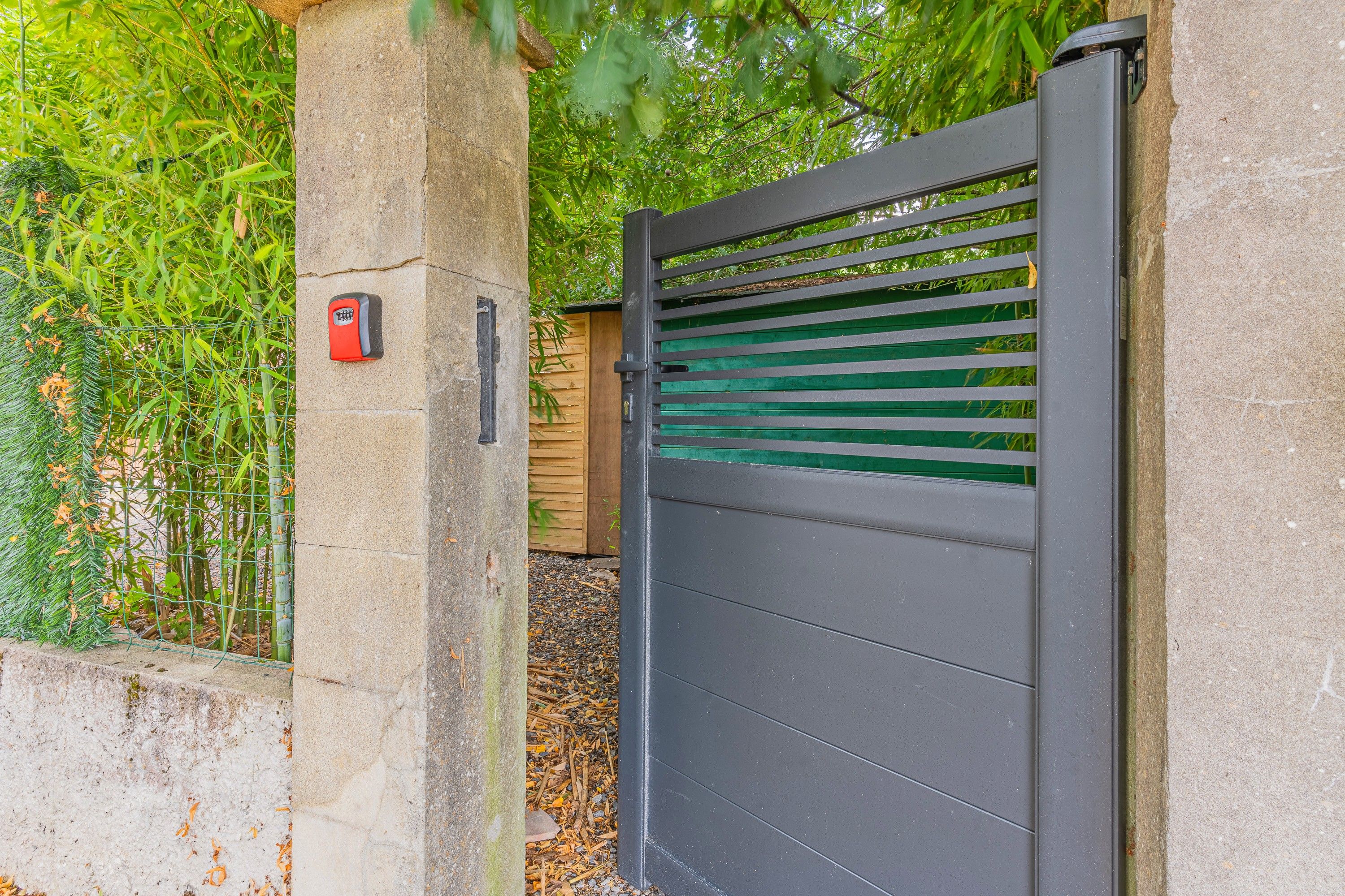 A gated entrance with a metal gate and a security keypad.
