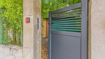A gated entrance with a metal gate and a security keypad.