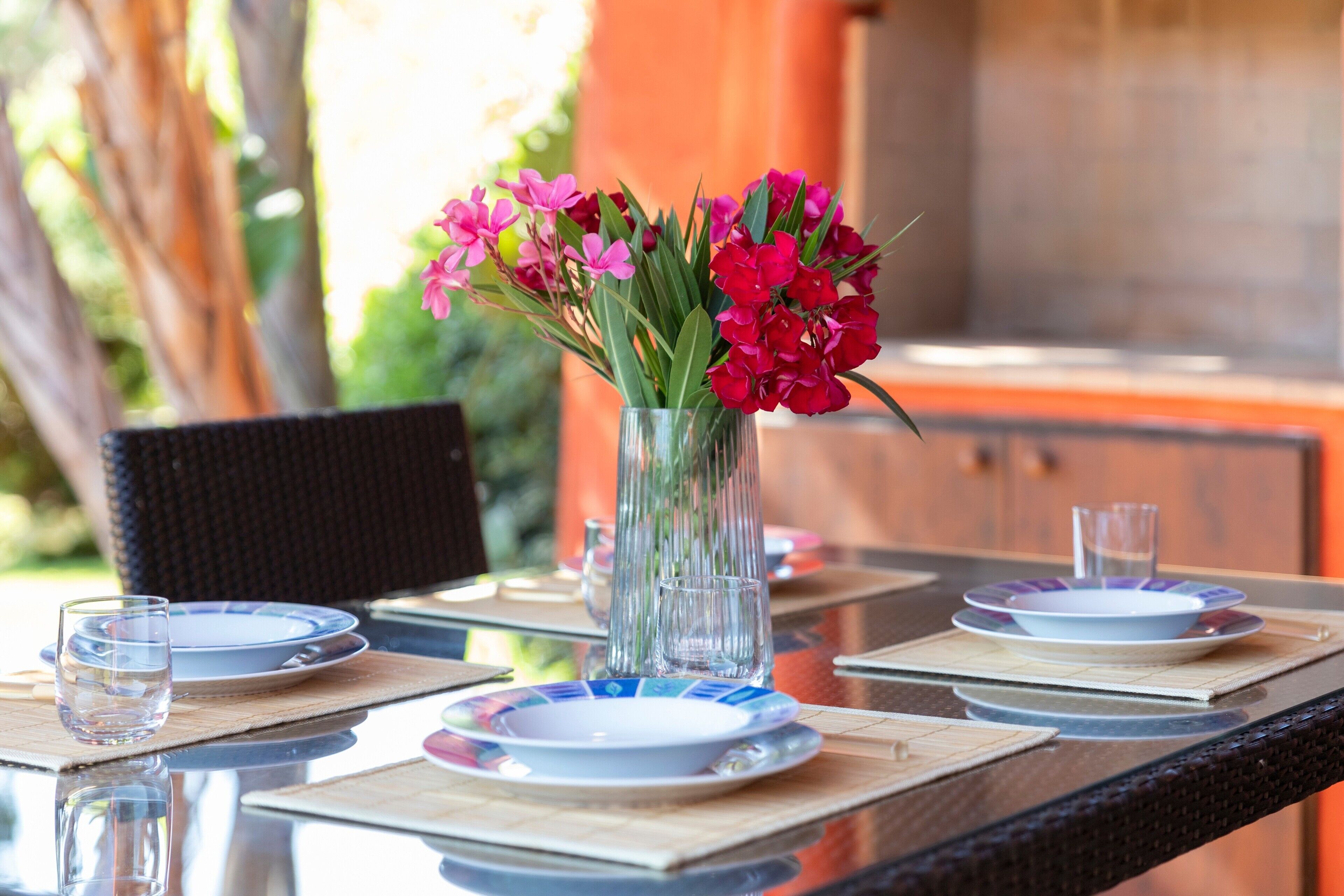 A dining table with plates, glasses, and a vase with flowers.
