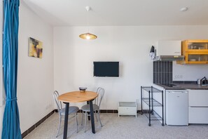 A compact kitchen with a refrigerator, a microwave, a sink, and a small dining area with a table and chairs.