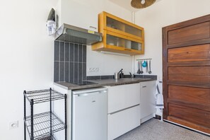 A compact kitchen with a dishwasher, a wooden cabinet, and a metal rack.