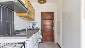A kitchen with a built-in oven, a wooden door, and a tiled backsplash. - Spacious 22 m2 Studio in the Village Center n1 (Charleval)