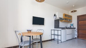 A compact kitchen with a TV, a small dining table, and chairs. - Spacious 22 m2 Studio in the Village Center n1 (Charleval)
