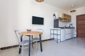 Una cocina compacta con televisor, una pequeña mesa de comedor y sillas.