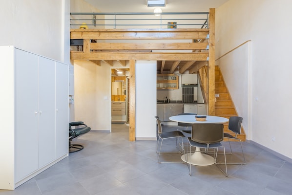Une pièce de style loft comprenant un coin repas, un escalier et une cuisine.