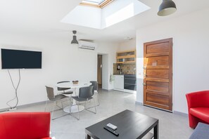Un soggiorno moderno con zona pranzo, cucina e un divano rosso.