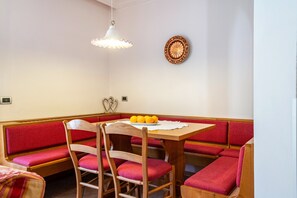 Un comedor con una mesa de madera, bancos acolchados rojos y una lámpara colgante blanca.