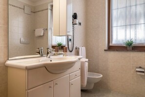 Ein Badezimmer mit einem Doppelwaschbecken, Toilette, Handtuchhalter, Spiegel und einem Fenster mit Blick.