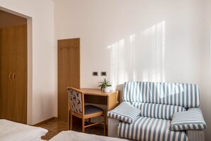 Ein Schlafzimmer mit einem Bett, einem Schreibtisch mit Stuhl, einem gestreiften Sofa und einem Kleiderschrank.