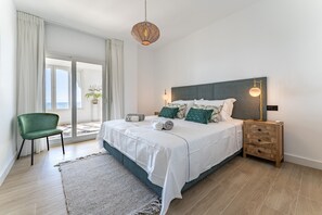 A bedroom with a bed, bedside table, lamp, chair, and a view through a glass door.