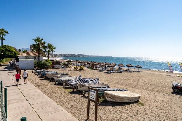 A beach with umbrellas, lounge chairs, and a sign indicating a designated area.