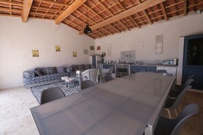 Une pièce spacieuse avec un haut plafond en bois, une table à manger avec des chaises, un canapé et un coin cuisine équipé de placards et d’un four à micro-ondes.