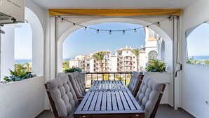 Un balcon avec une table et des chaises, une vue sur les immeubles et des guirlandes lumineuses.