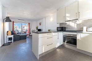 Una cocina moderna con armarios blancos, horno empotrado y encimera de granito.