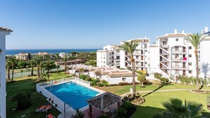 Un complexe hôtelier doté d’une piscine, de palmiers et offrant une vue sur la mer.