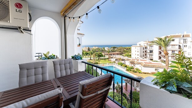Un balcon avec vue sur la piscine, une table avec des chaises et un onduleur intelligent fixé au mur.