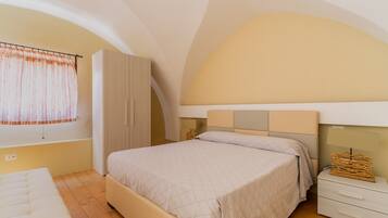 A bedroom with a bed, a wardrobe, a nightstand, and a window with curtains.