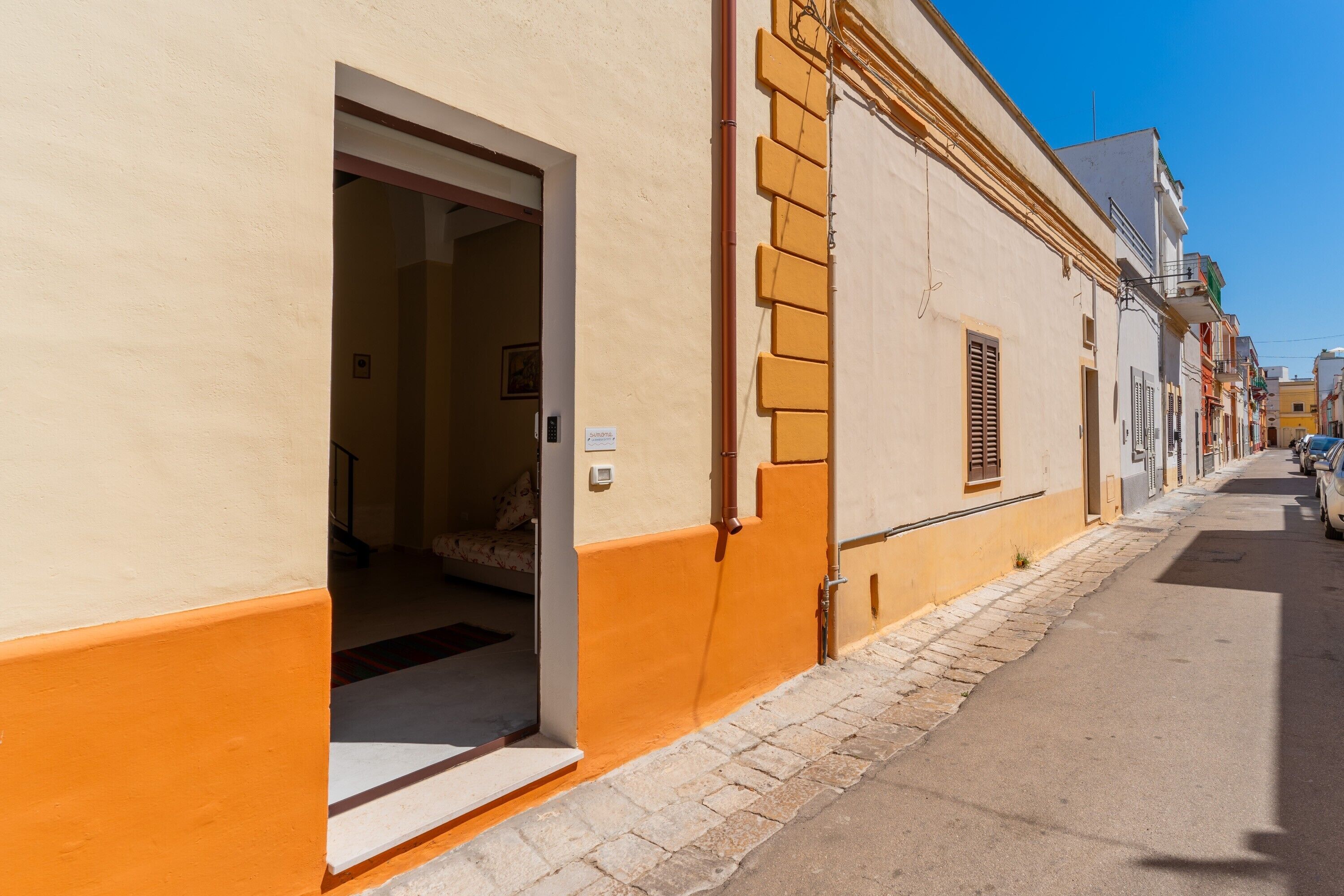 Une rue étroite avec un bâtiment dont la porte donne accès à un espace intérieur.