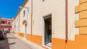 A street view with a building featuring a door, a window, and a visible pipe. - Apartment 'Simone' with Wi-Fi and Air Conditioning (alezio)