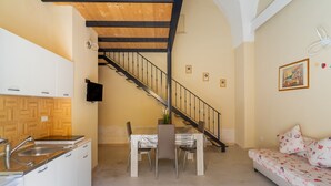 A compact living space with a kitchen, dining area, staircase, and a sofa. - Apartment 'Simone' with Wi-Fi and Air Conditioning (alezio)