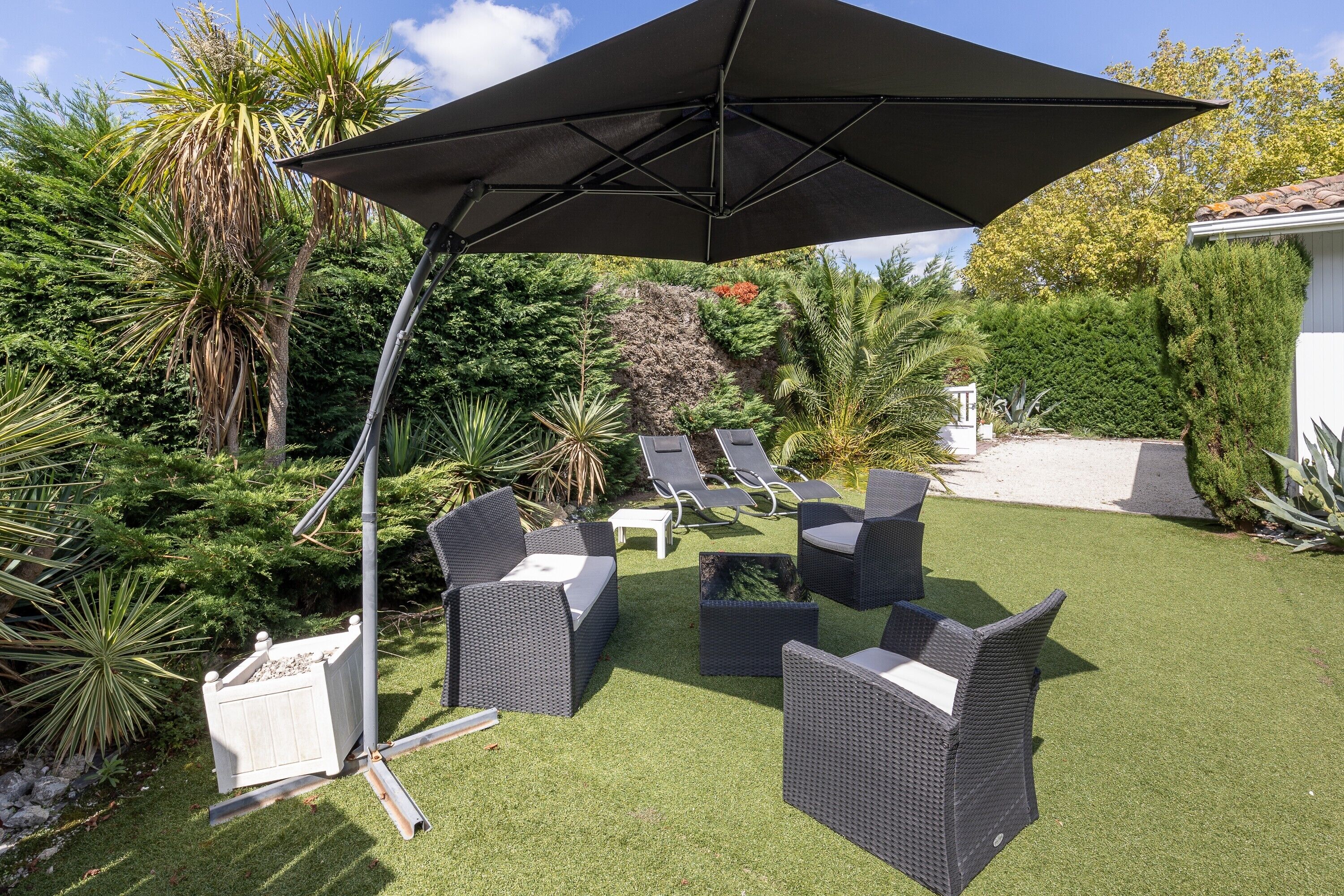An outdoor patio with wicker furniture, a large umbrella, and a well-maintained lawn.