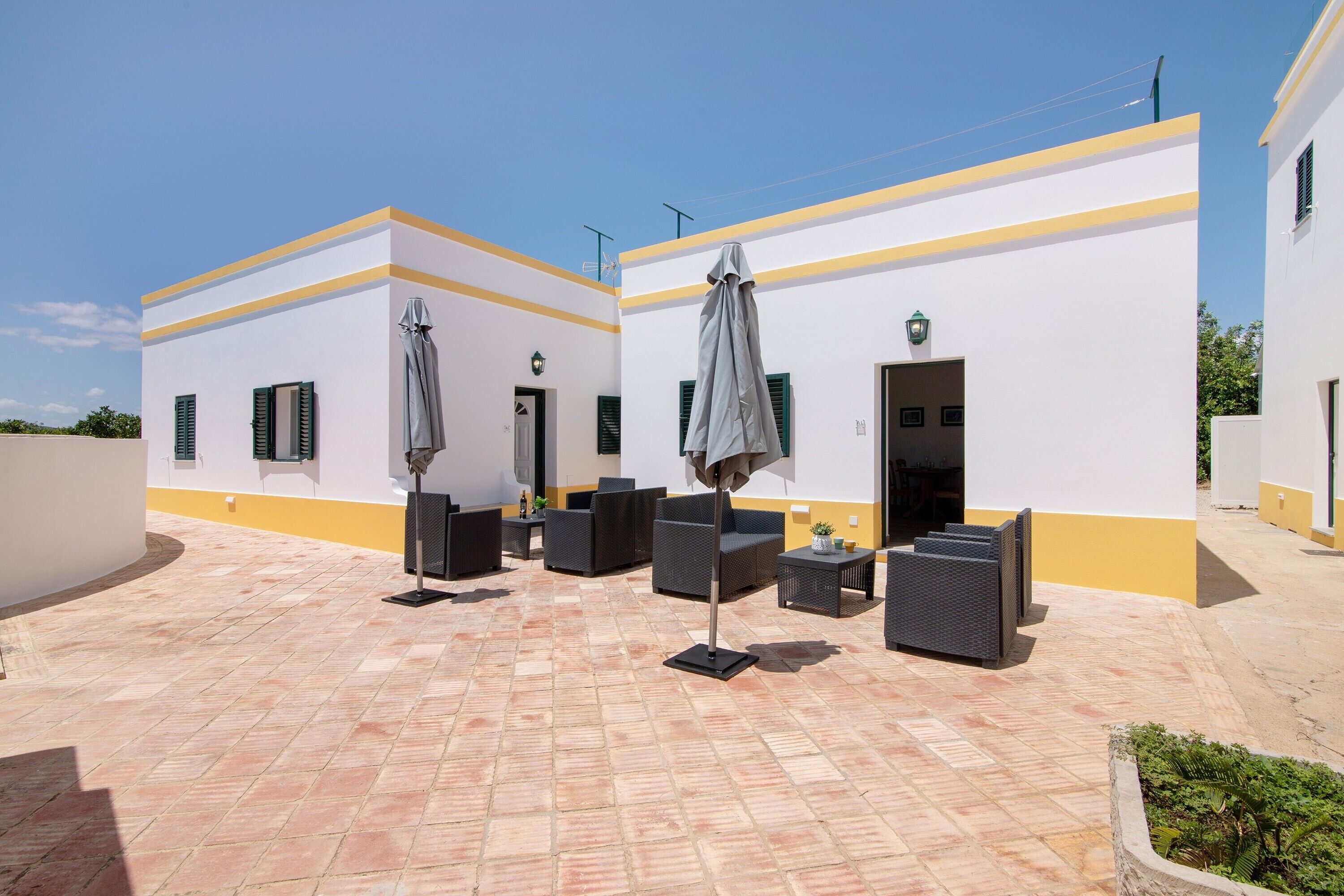 A courtyard with outdoor seating, a covered area, and a building with a yellow and white facade.