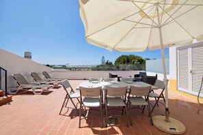 A terrace with a table and chairs, a large umbrella, and a view of the landscape. - Holiday Home 'Quinta Alegre Tavira T3' with Shared Pool, Wi-Fi and Air Conditioning (Luz)