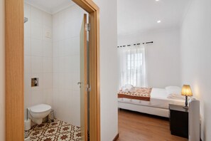 A bathroom with a toilet, shower, and patterned floor tiles. - Holiday Home 'Quinta Alegre Tavira T3' with Shared Pool, Wi-Fi and Air Conditioning (Luz)
