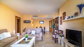 Una sala de estar con sofá, mesa de centro, televisor y mueble para televisión.