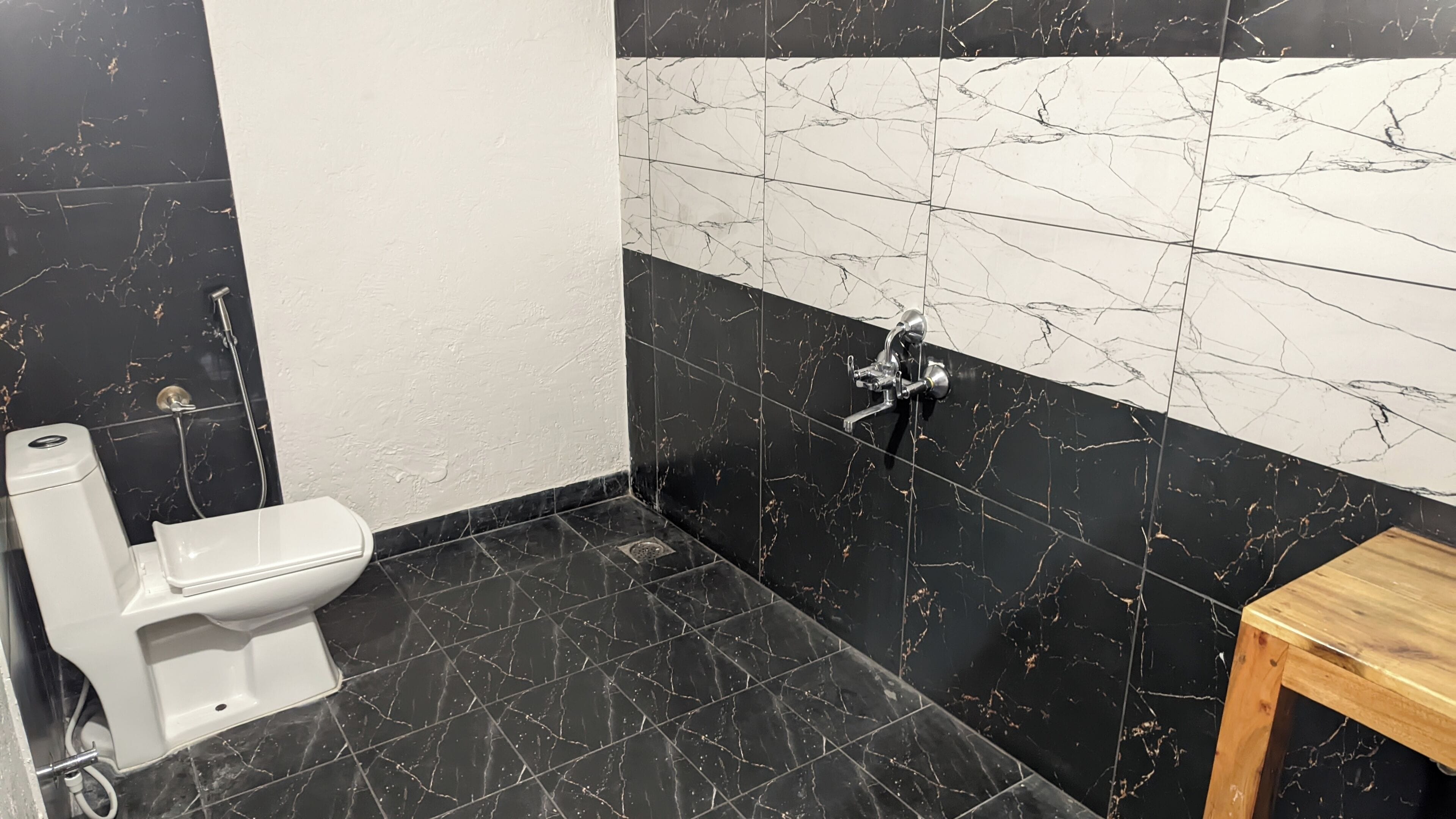 A bathroom with a toilet, a shower, and a wooden stool.