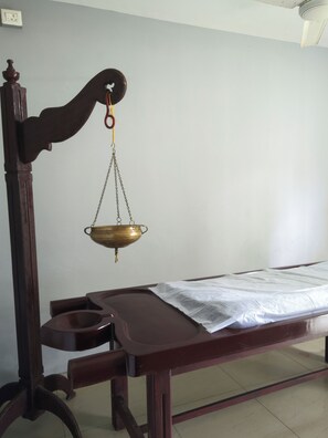 A wooden bed with a metal frame, a white sheet, and a brass scale hanging from the headboard.