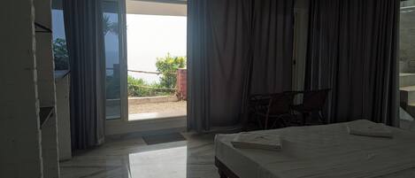 A hotel room with a bed, a chair, and a view of the outside.
