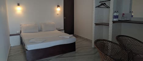 A hotel room with a bed, two bedside tables, a chair, a wardrobe, and a mirror.