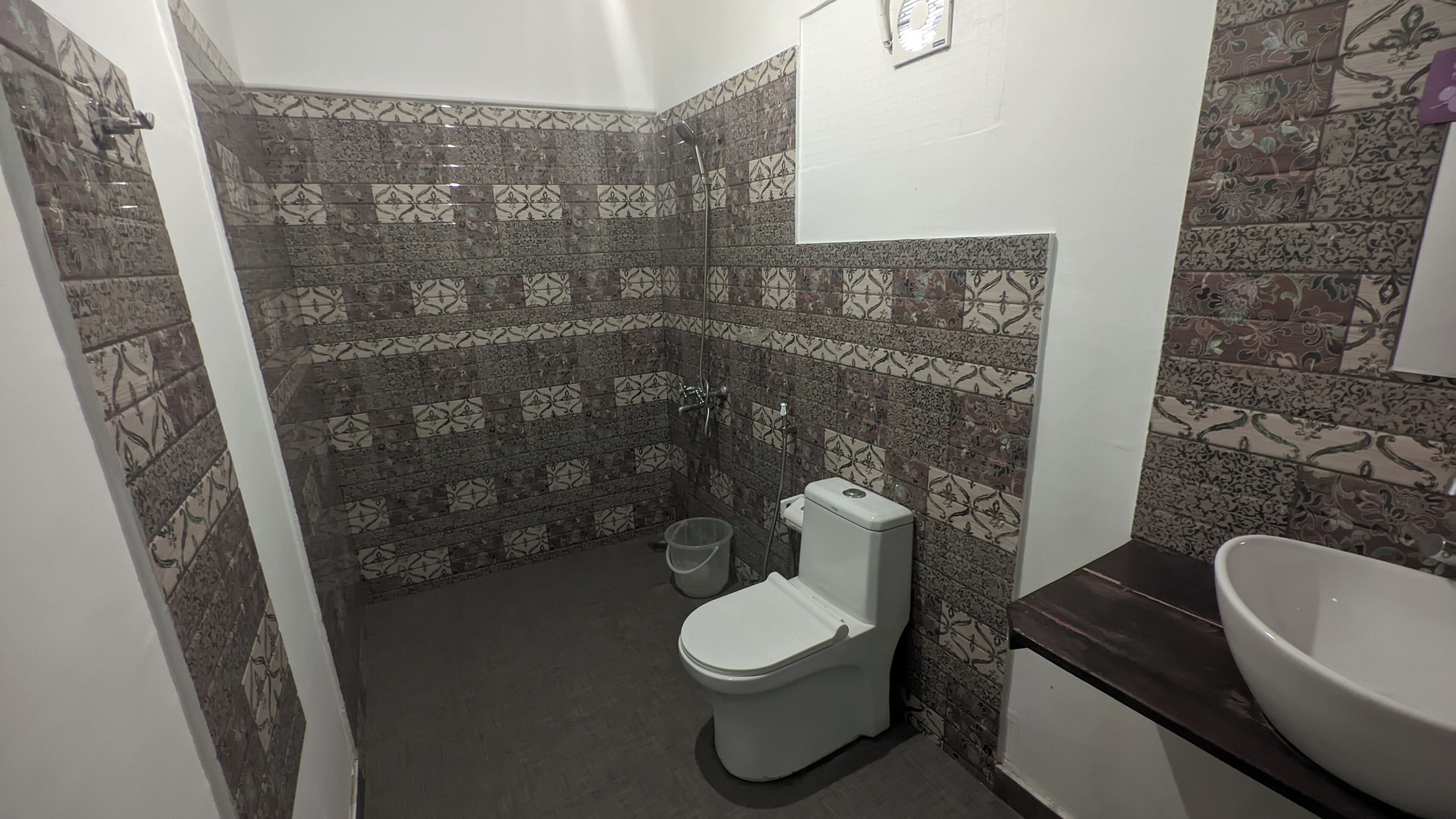 A bathroom with patterned tiles, a toilet, a sink, and a shower.
