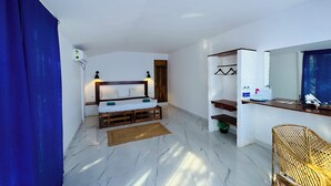 Een slaapkamer met een bed, nachtkastjes, een houten hoofdbord, een kledingkast, een spiegel en een rieten stoel.