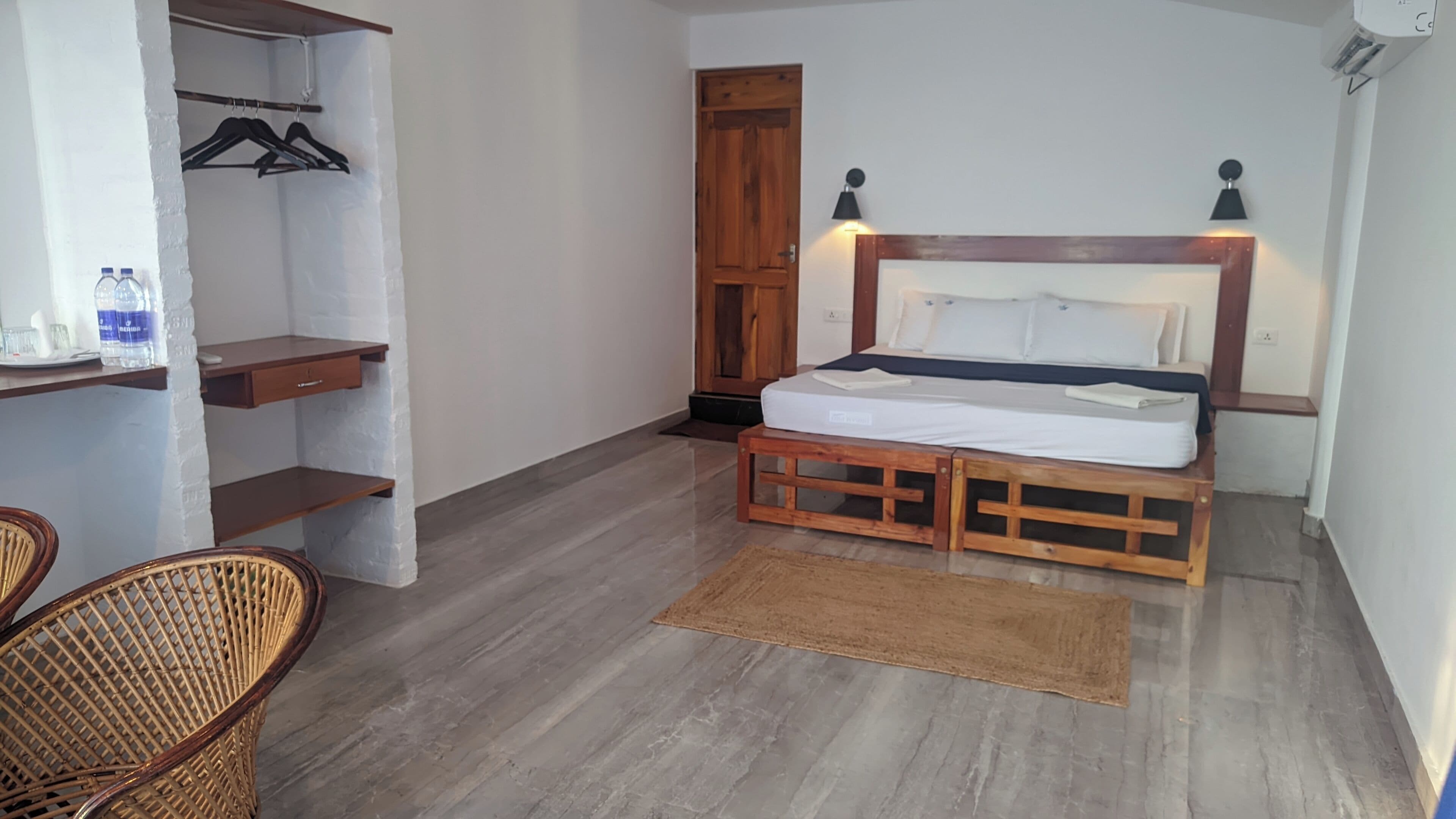 A bedroom with a wooden bed, a wardrobe, a chair, and a small table.
