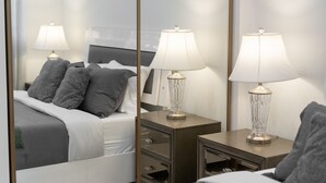 Une chambre d’hôtel comprenant un lit, deux tables de chevet avec des lampes, un miroir et une commode.